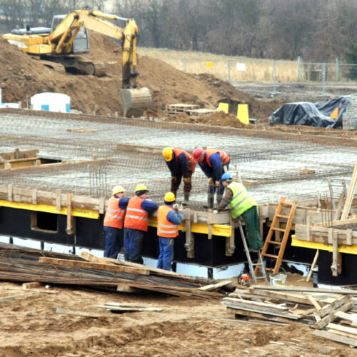 Photo Editing Workers in orange vests preparing a concrete foundation pour