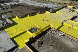 created by dji camera Aerial view of yellow waterproofing across a building footprint at Enso Village