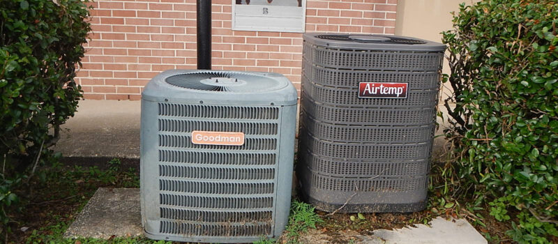 Residential AC condensing units beside a brick wall
