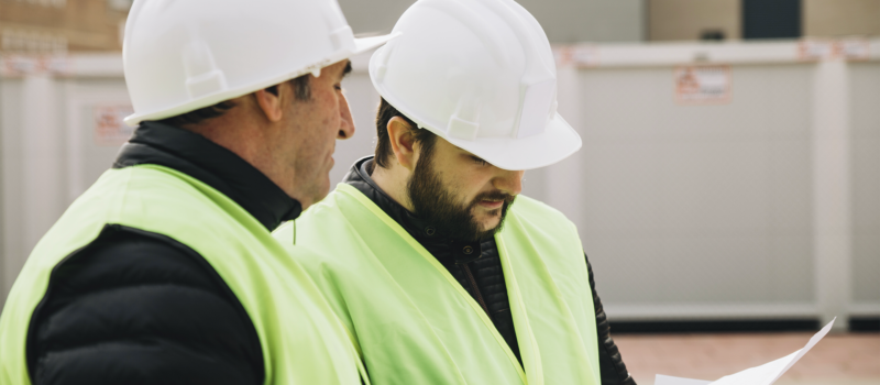Two construction professionals examining blueprints during facility planning