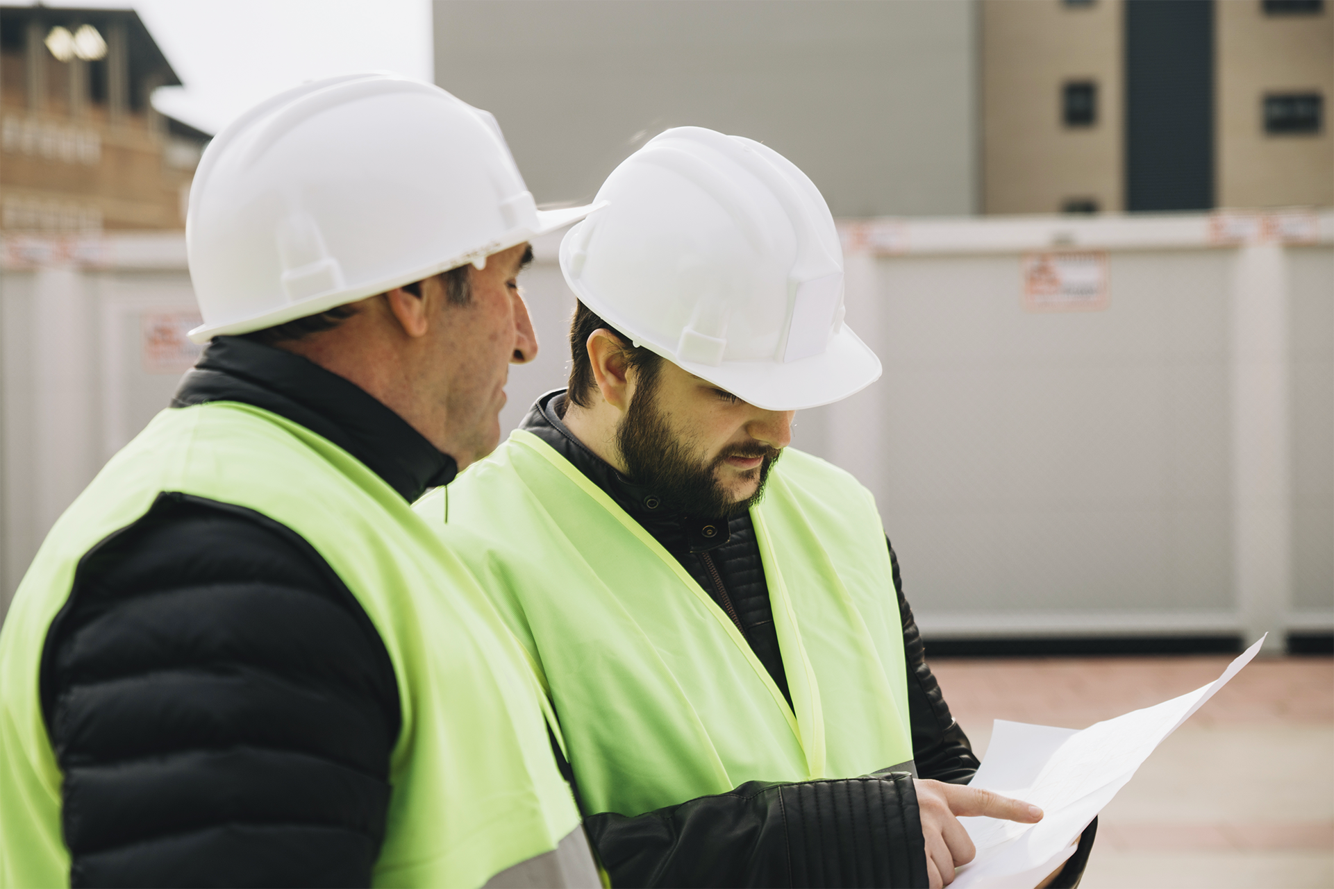Two construction professionals examining blueprints during facility planning – zumBrunnen construction consulting