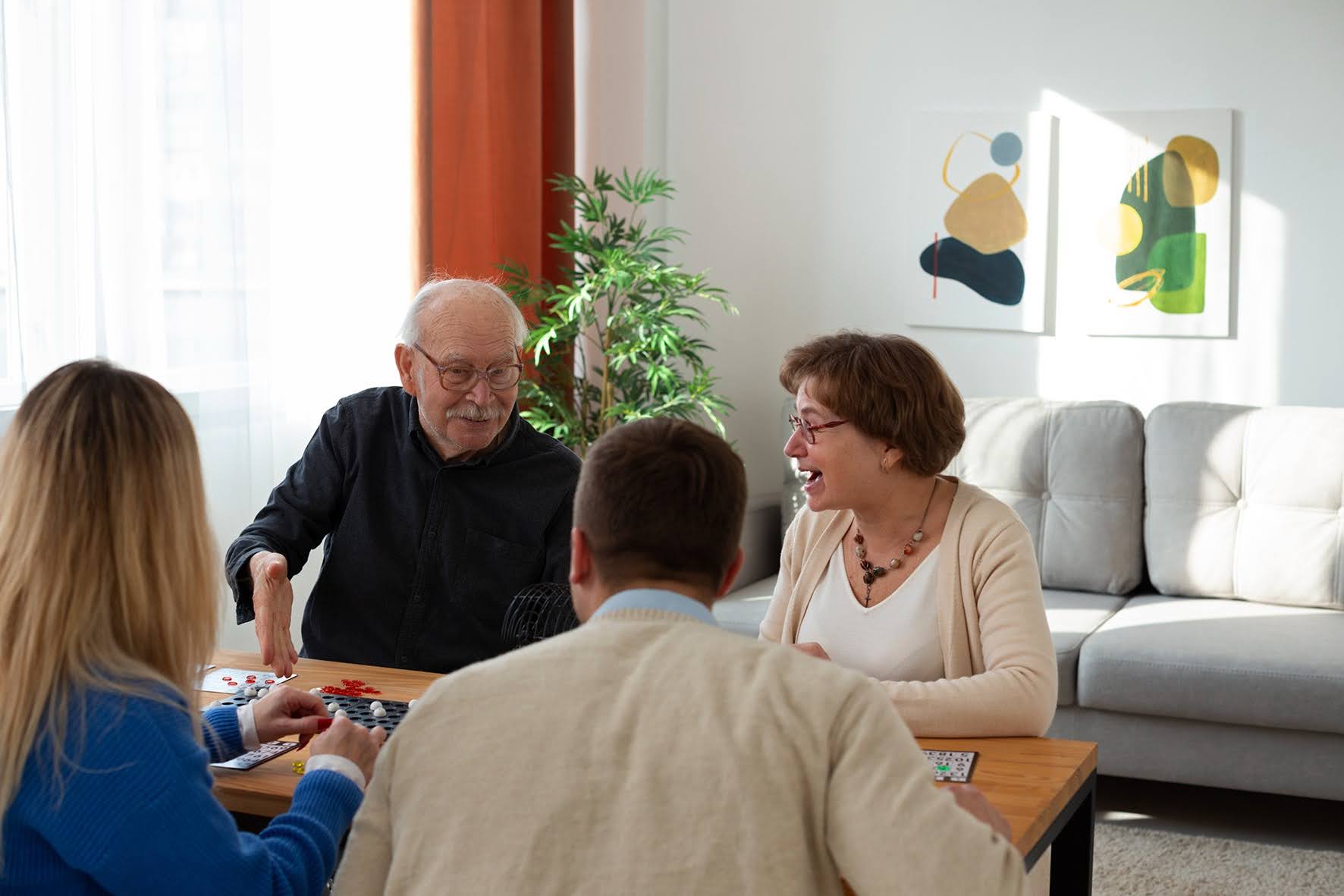 Older couple and younger couple sitting at a coffee table playing a game